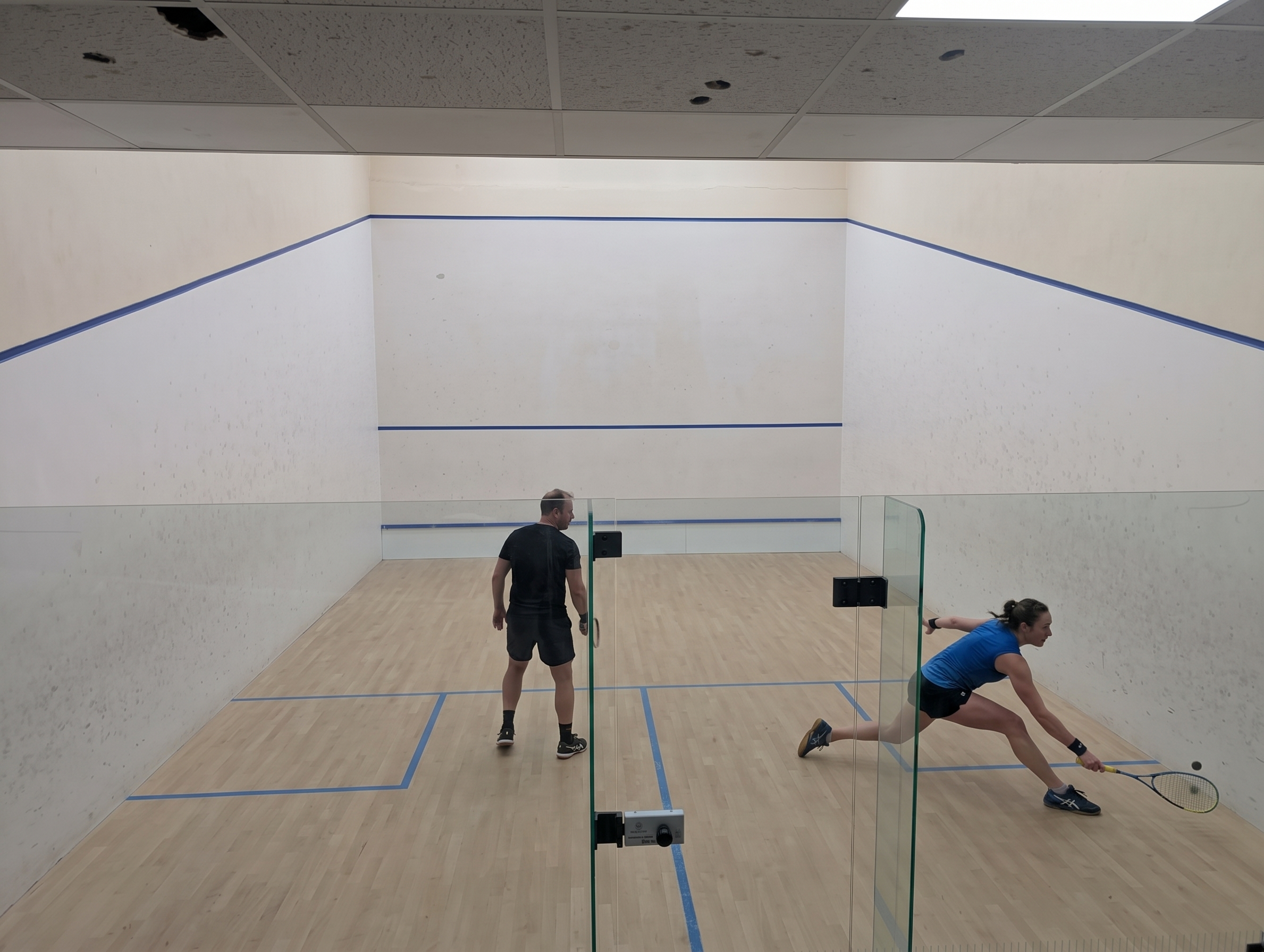 Players in a squash match on a glass-backed court at St Augustine's Sports Centre